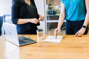 Two people standing at a table with a laptop and notepad discussing the benefits of embedded BI.